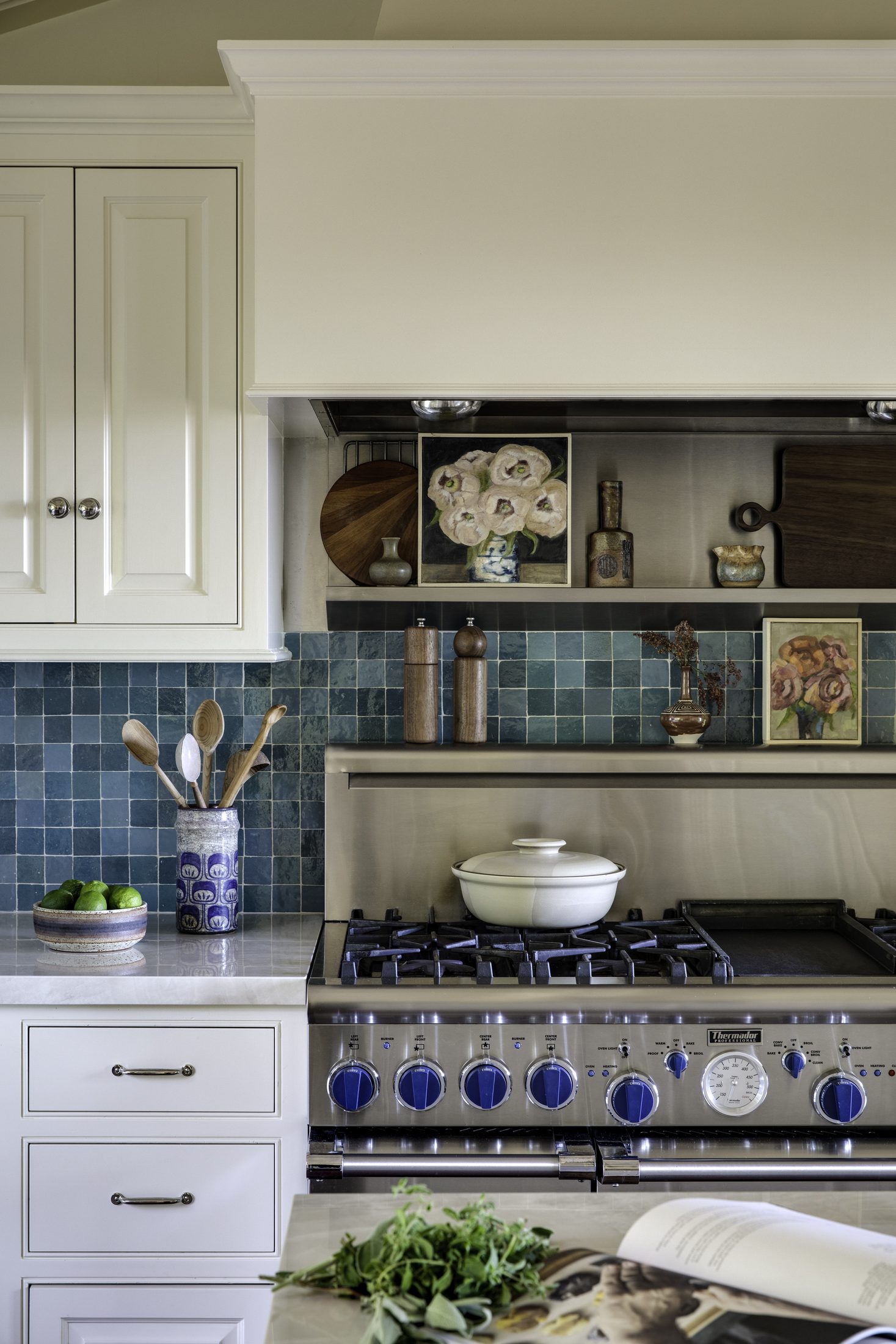 Range wall with blue tile backsplash and open cookbook shelving
