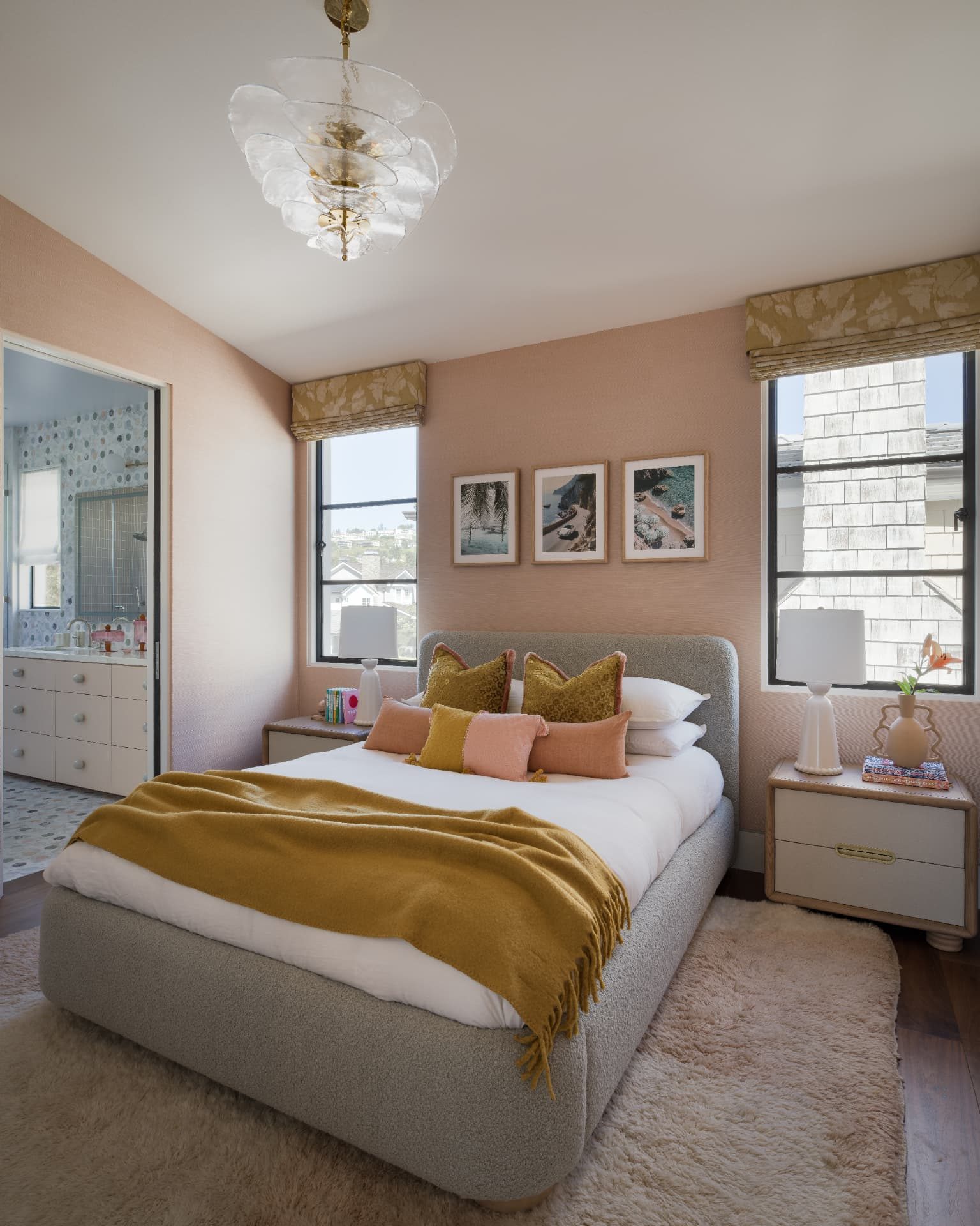 Blush bedroom with a bouclé bed, ochre throw, and coastal prints