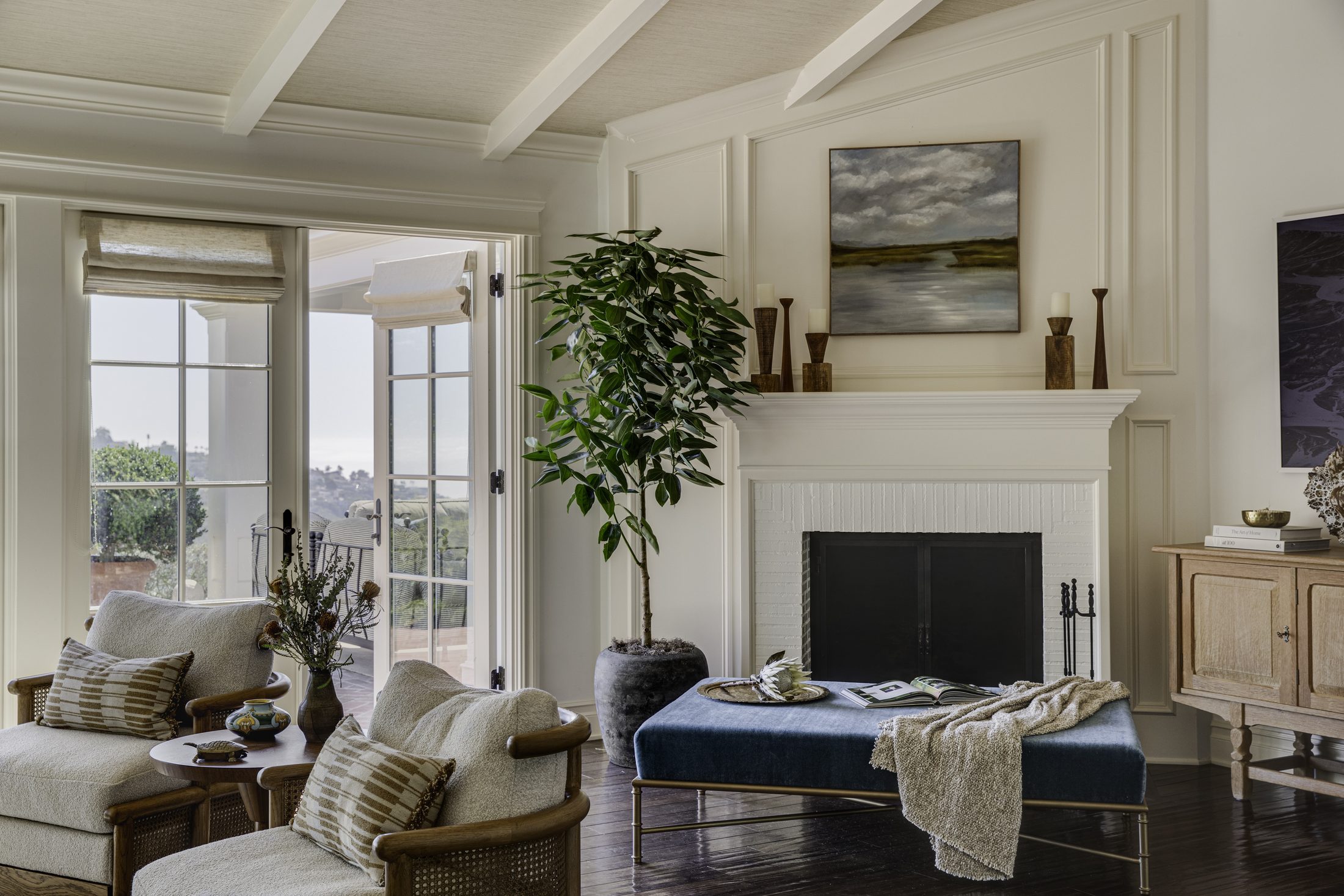 Sitting room with fireplace, potted ficus, and a navy velvet bench