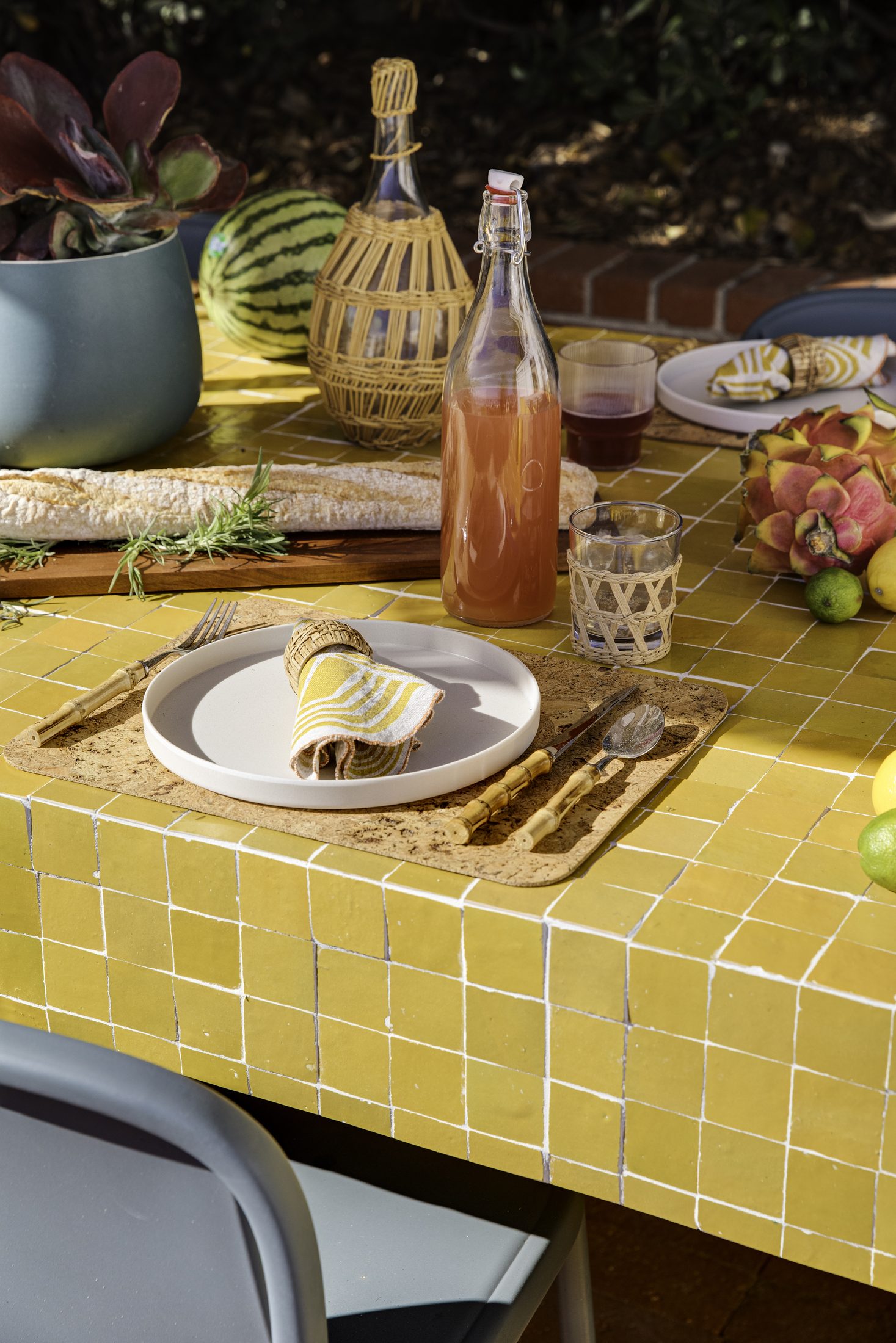 Table setting detail with citrus, glassware, and woven linens