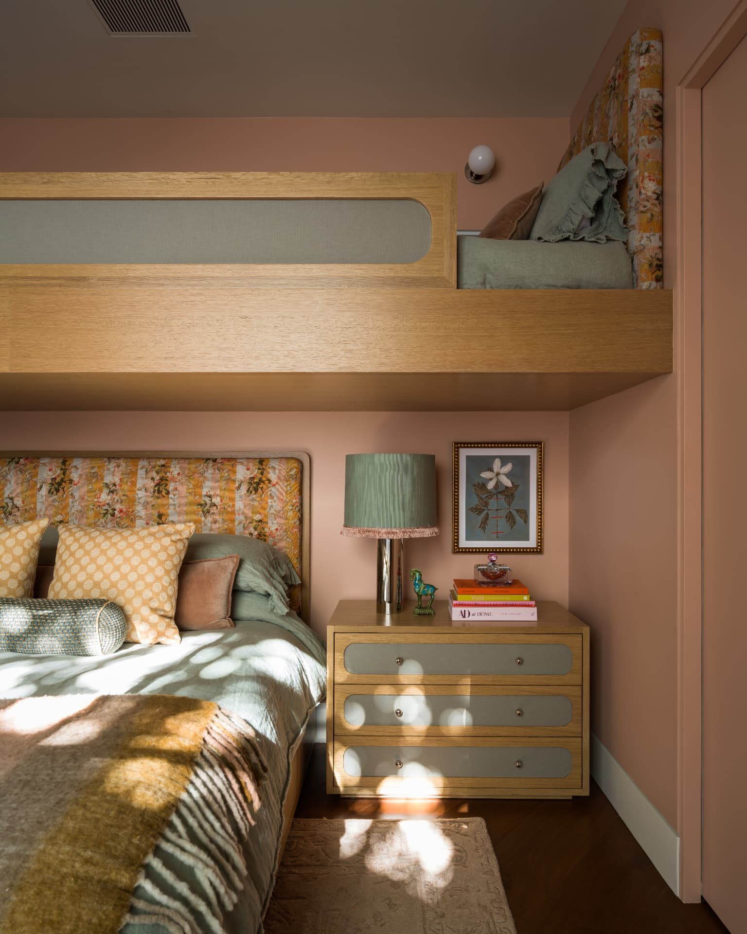 Bedside detail with a green pleated lamp and botanical artwork