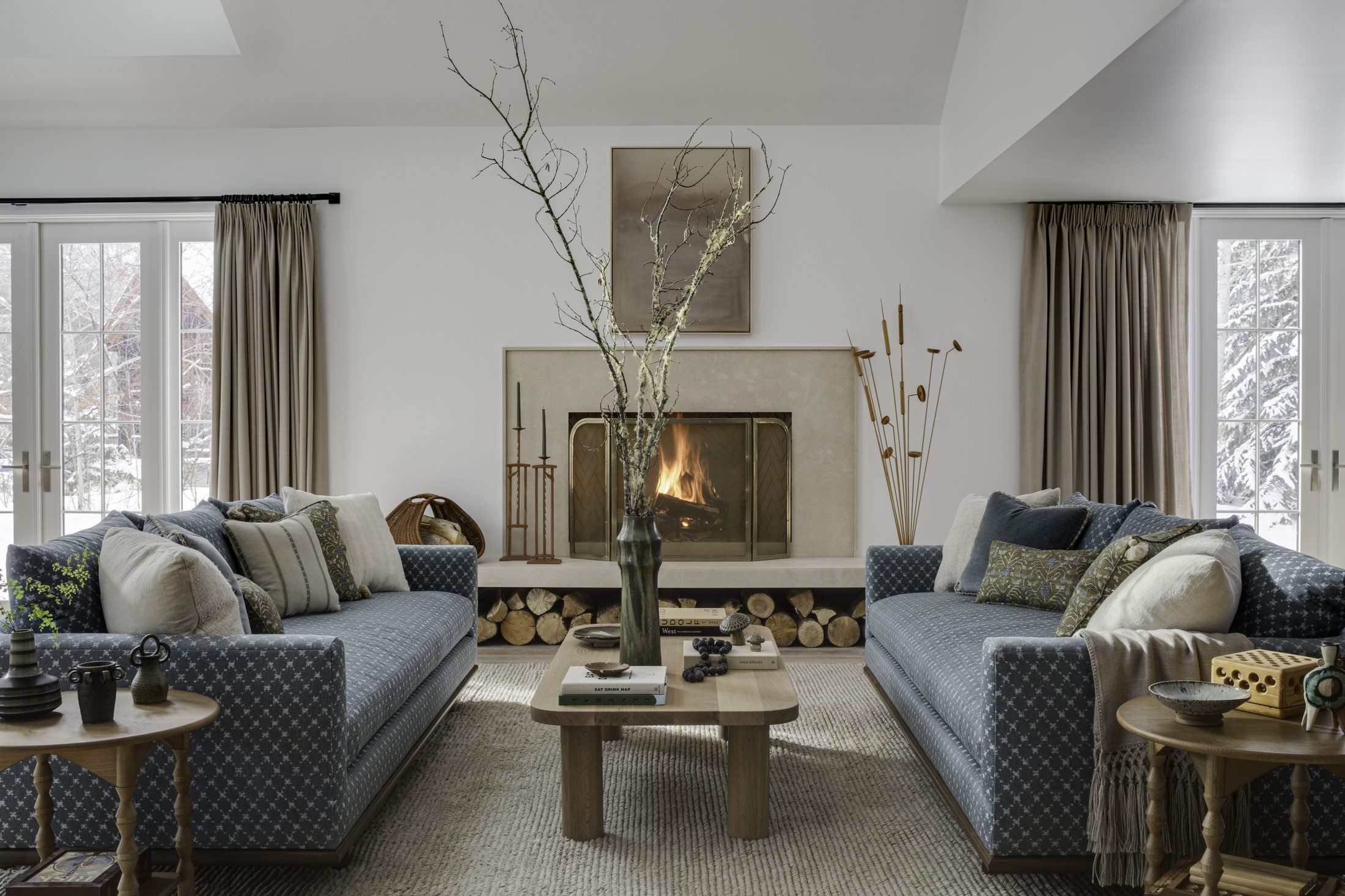 Great room with twin sofas flanking a lit stone fireplace
