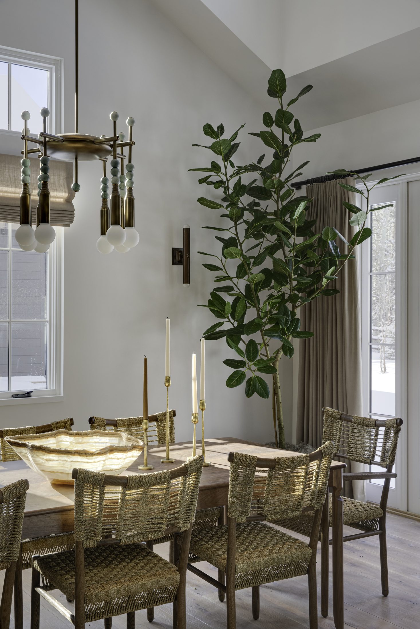Dining room with woven chairs and a sculptural brass chandelier