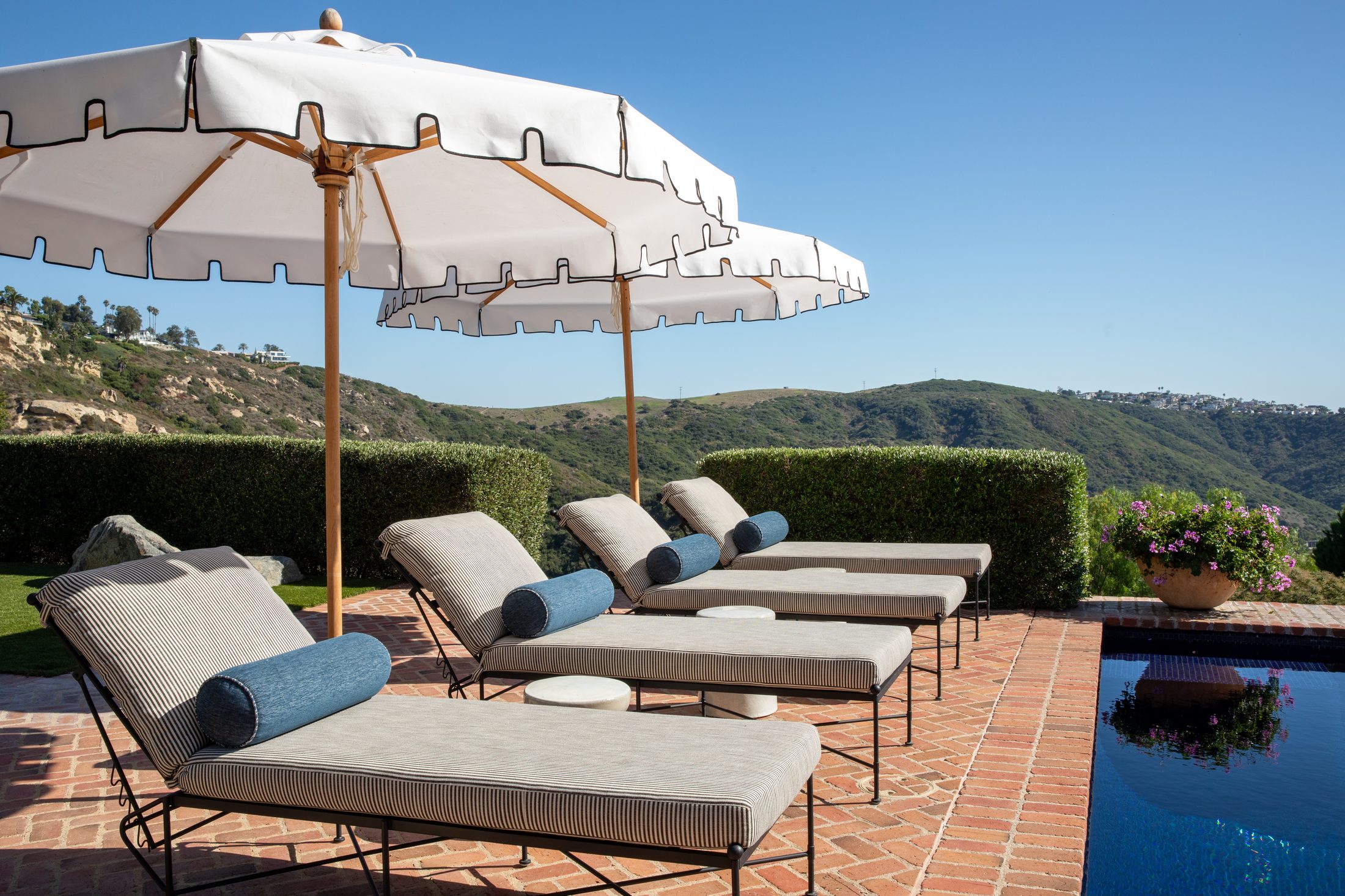 Poolside chaise lounges under scalloped umbrellas with canyon views