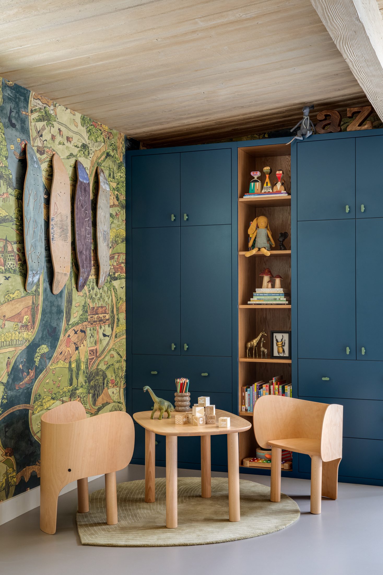 Children's room with mural wallpaper and deep blue joinery