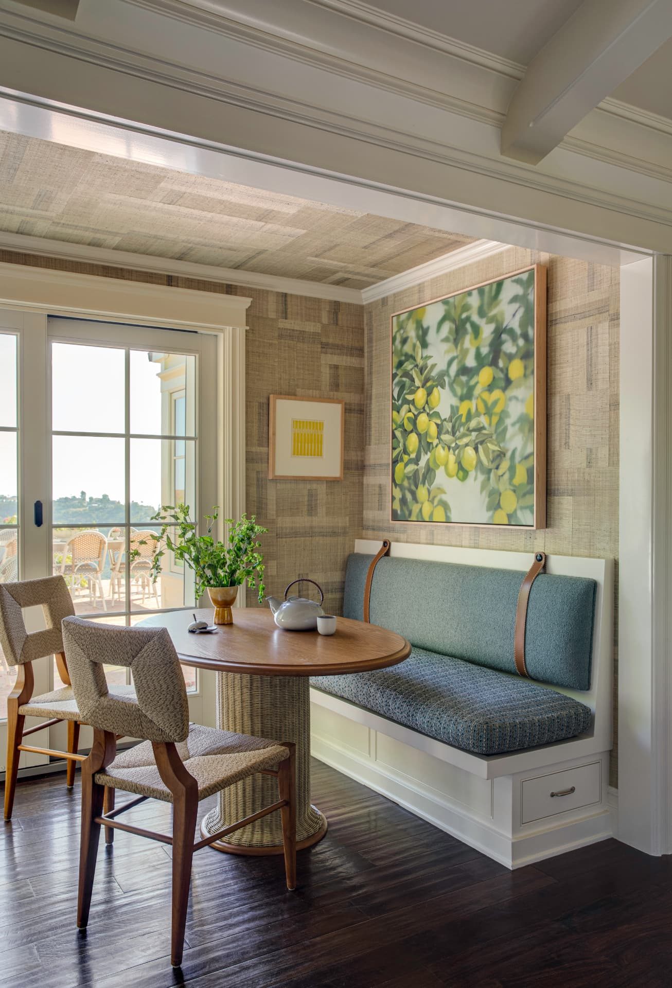 Banquette breakfast nook with grasscloth walls and a lemon tree painting