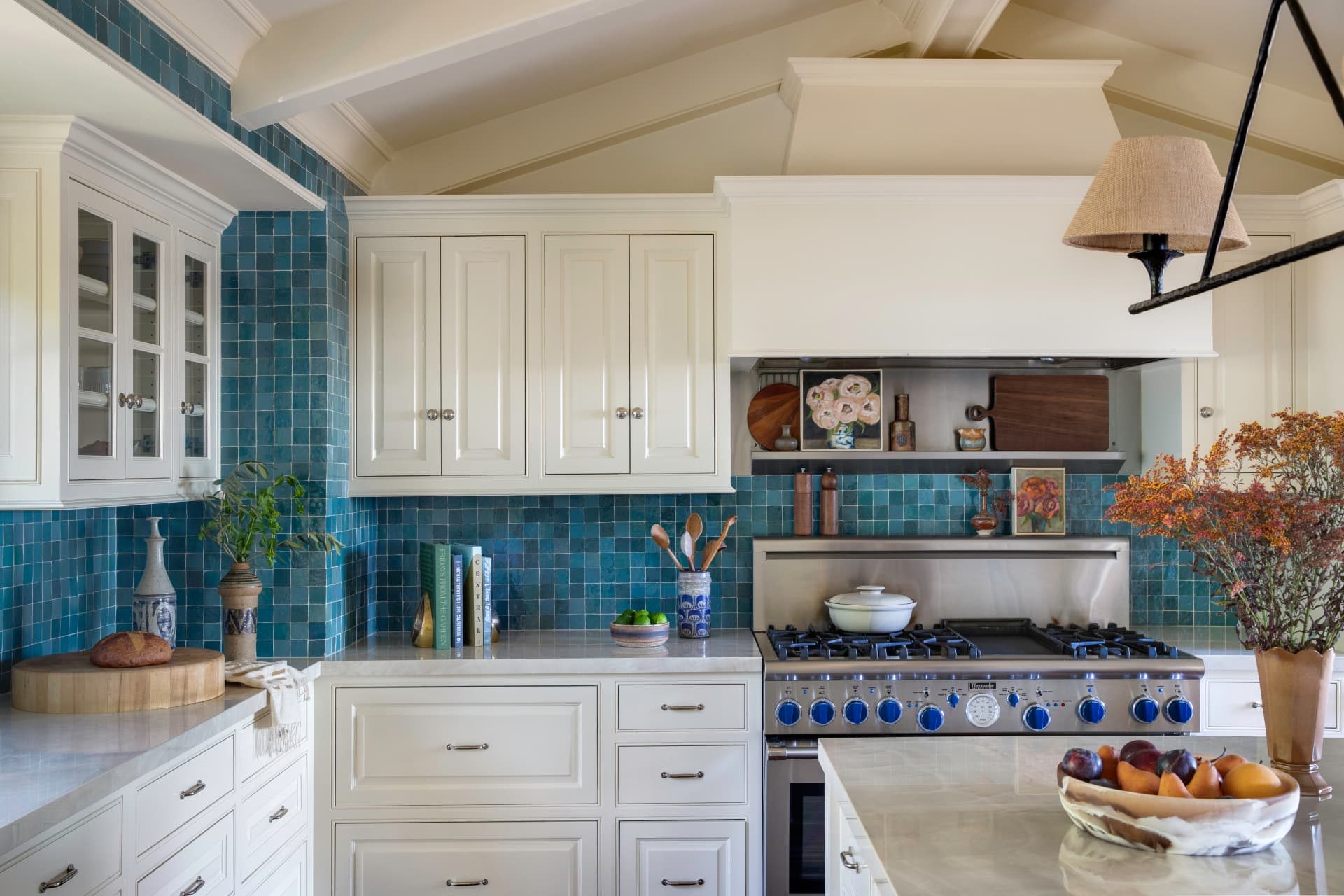 Kitchen with ivory cabinetry, blue zellige tile, and a vaulted beamed ceiling