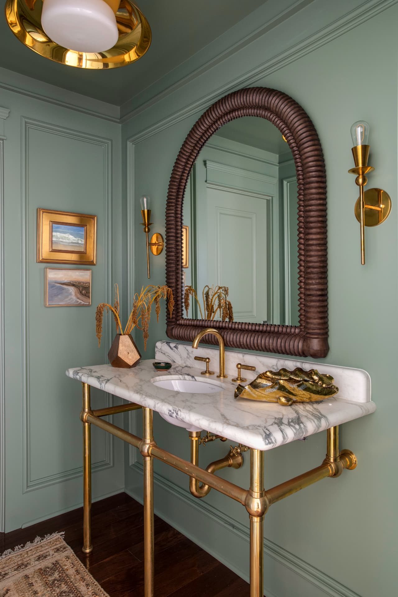 Powder room in sage green with a marble console sink and brass fittings